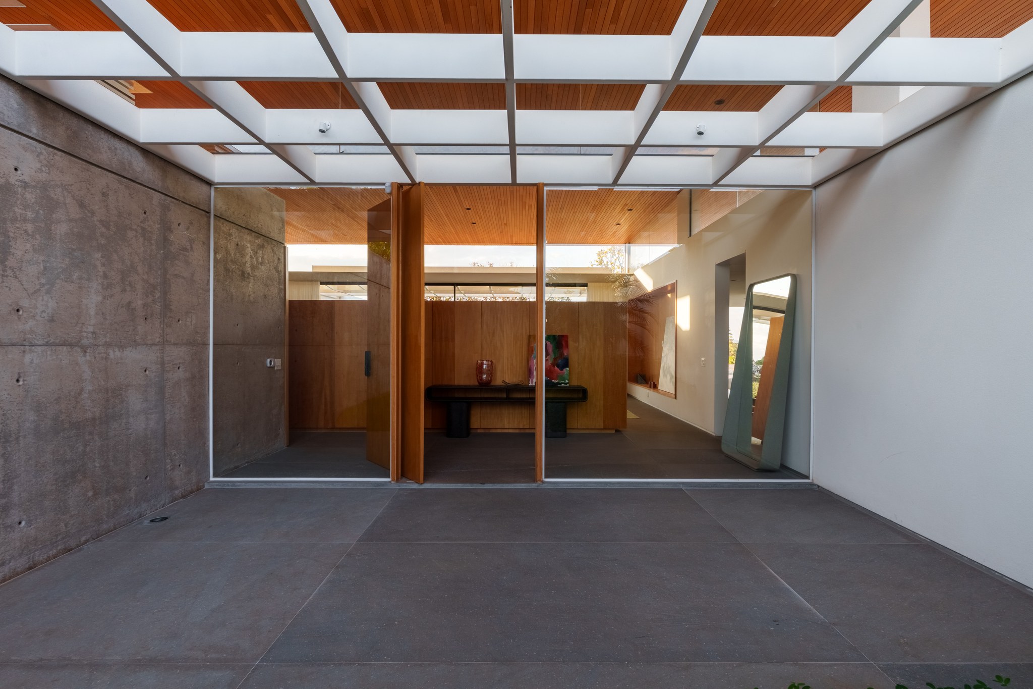 Espaço interno com paredes de concreto e teto em madeira, iluminado naturalmente