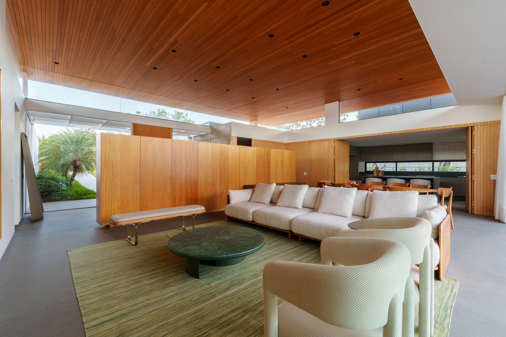 Sala de estar ampla com sofá branco, mesa redonda e teto de madeira