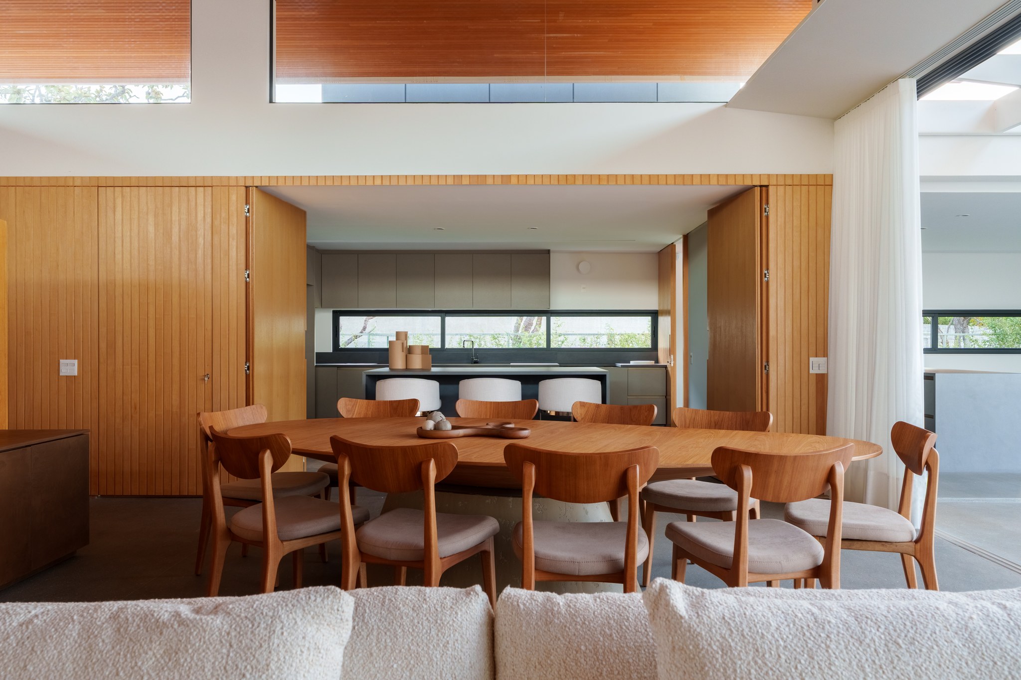 Sala de jantar com mesa de madeira e cortina branca ao lado