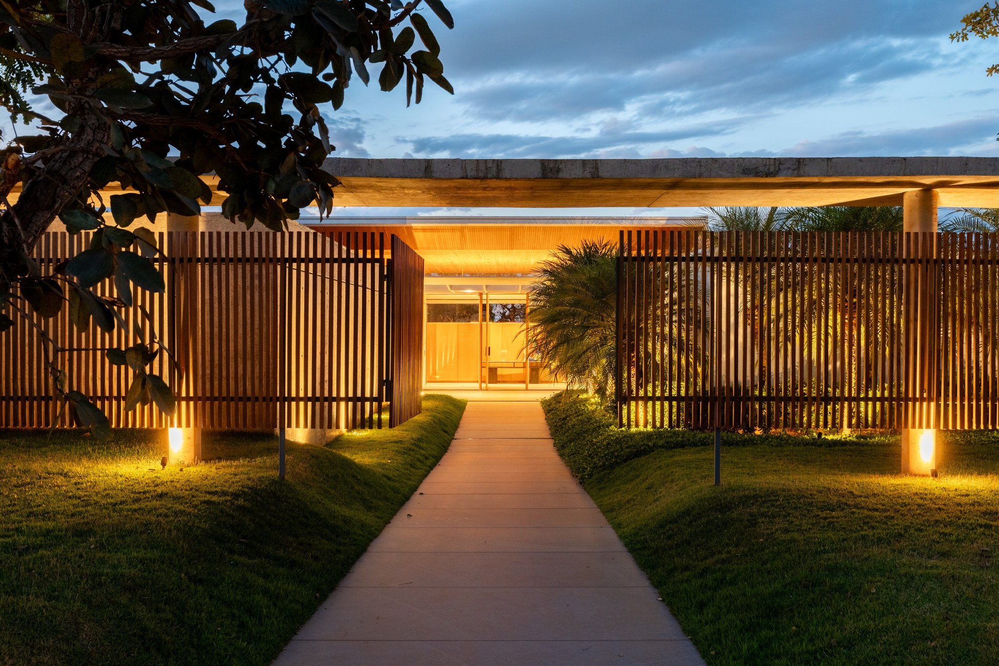 Entrada principal iluminada à noite com detalhes em madeira