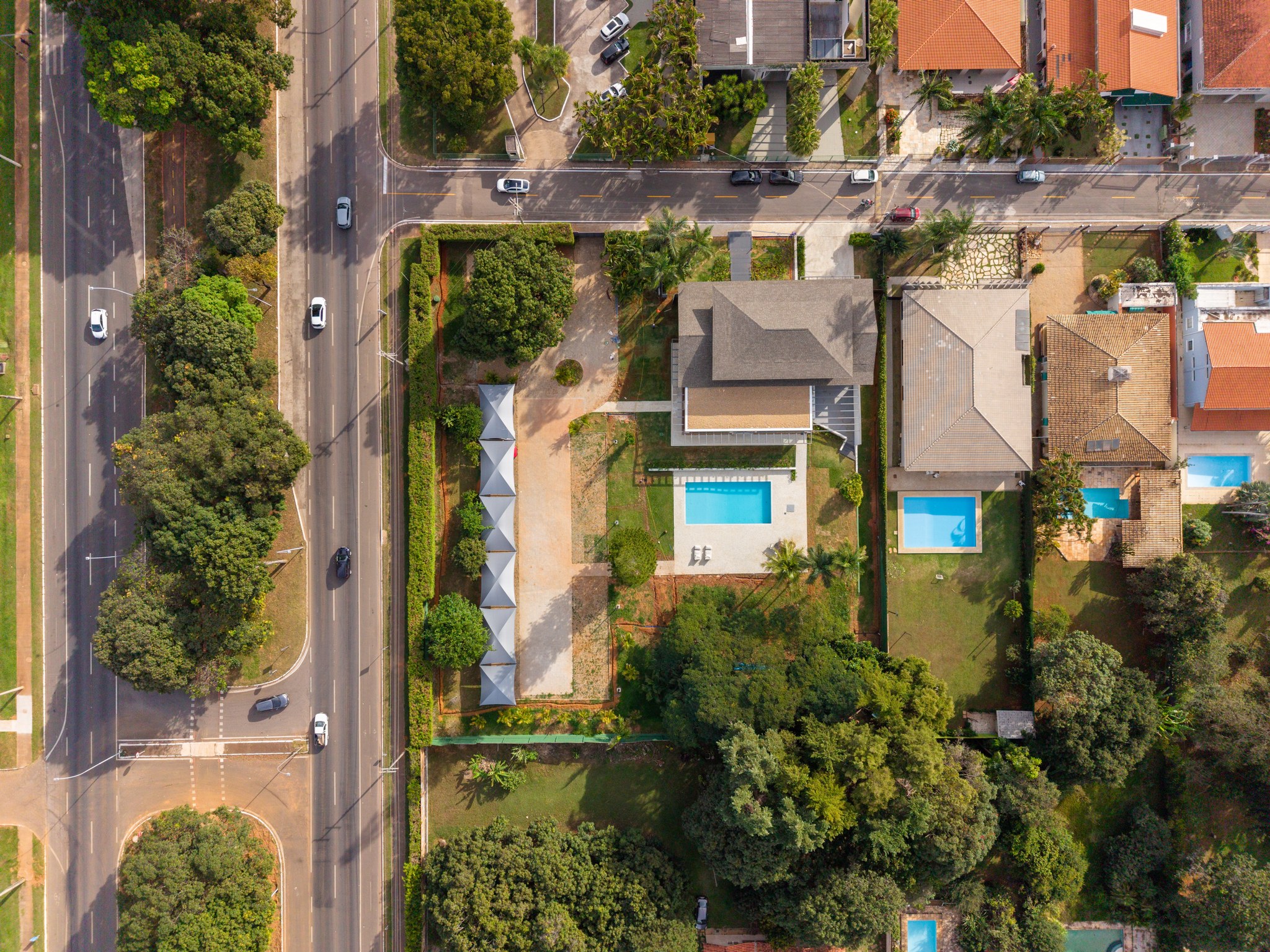 Vista aérea do terreno com piscina, pergolado de madeira e gramado entre árvores
