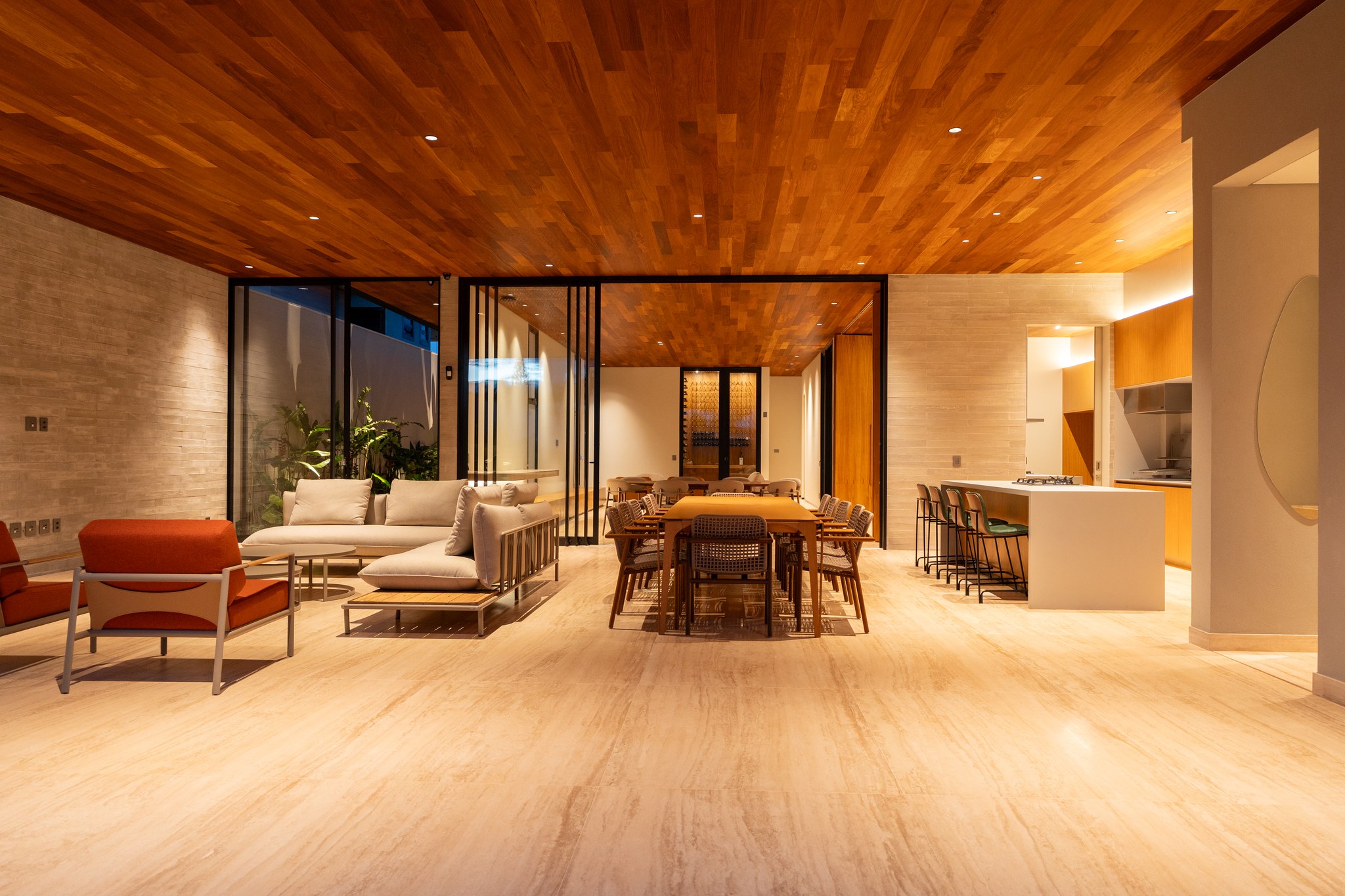 Sala de estar integrada à sala de jantar e cozinha, com poltronas coloridas e revestimento em pedra