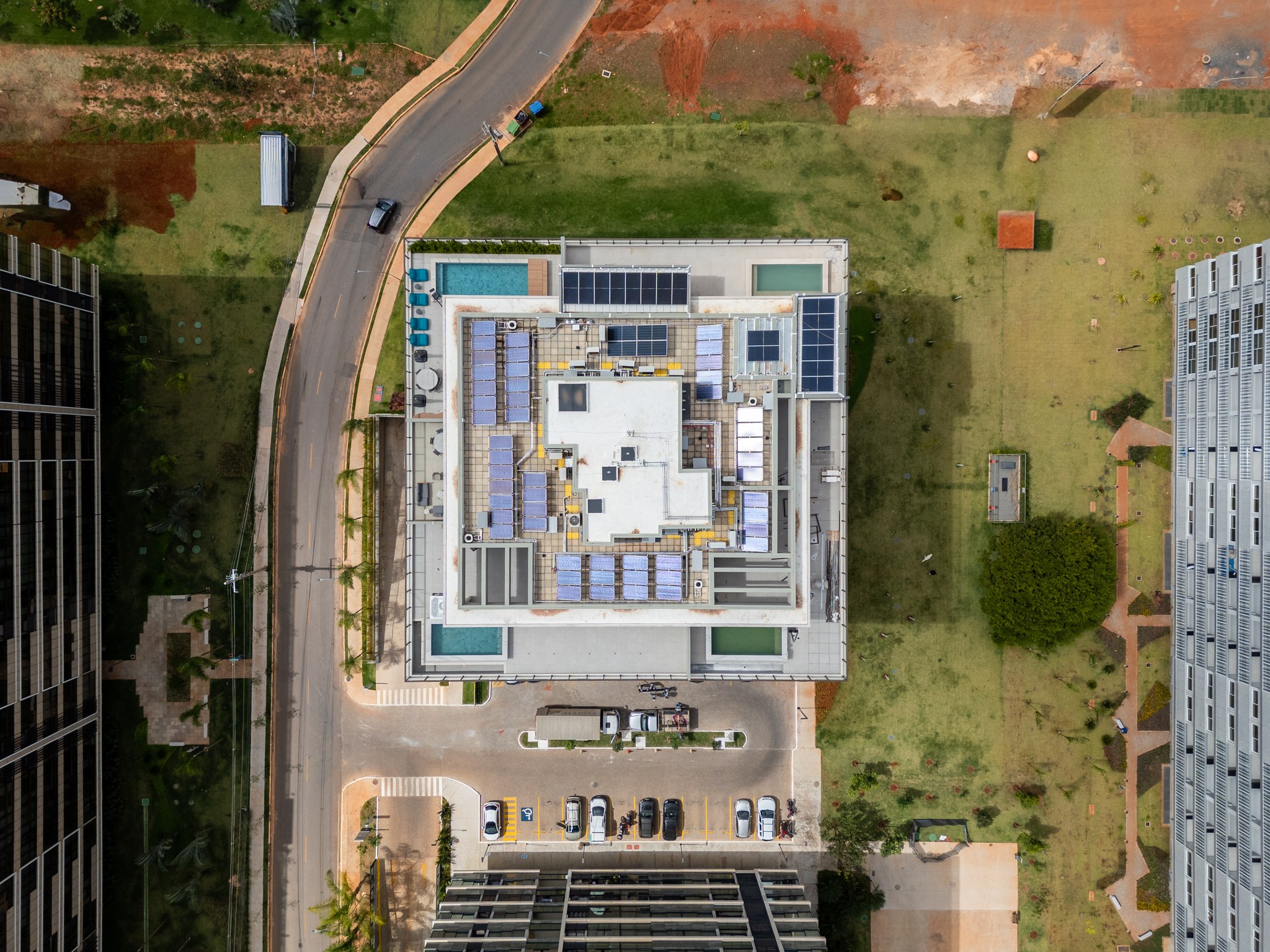 Vista aérea da cobertura do edifício, com piscinas, playground e painéis solares no terraço