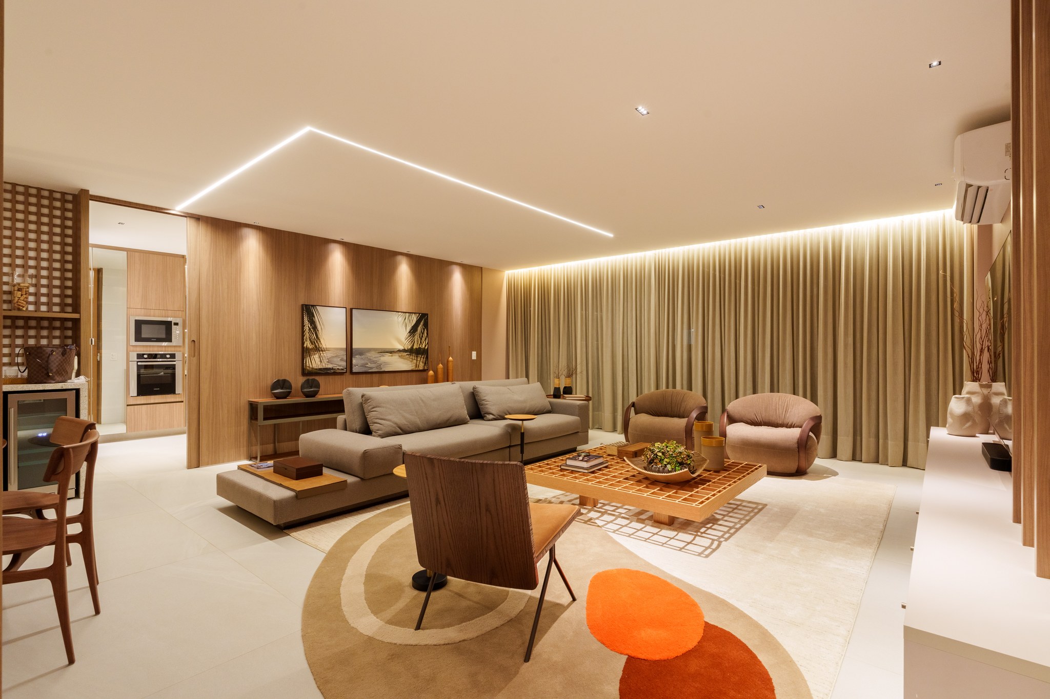 Sala de estar com sofá cinza, tapete circular colorido e poltronas marrons diante da mesa de centro vazada