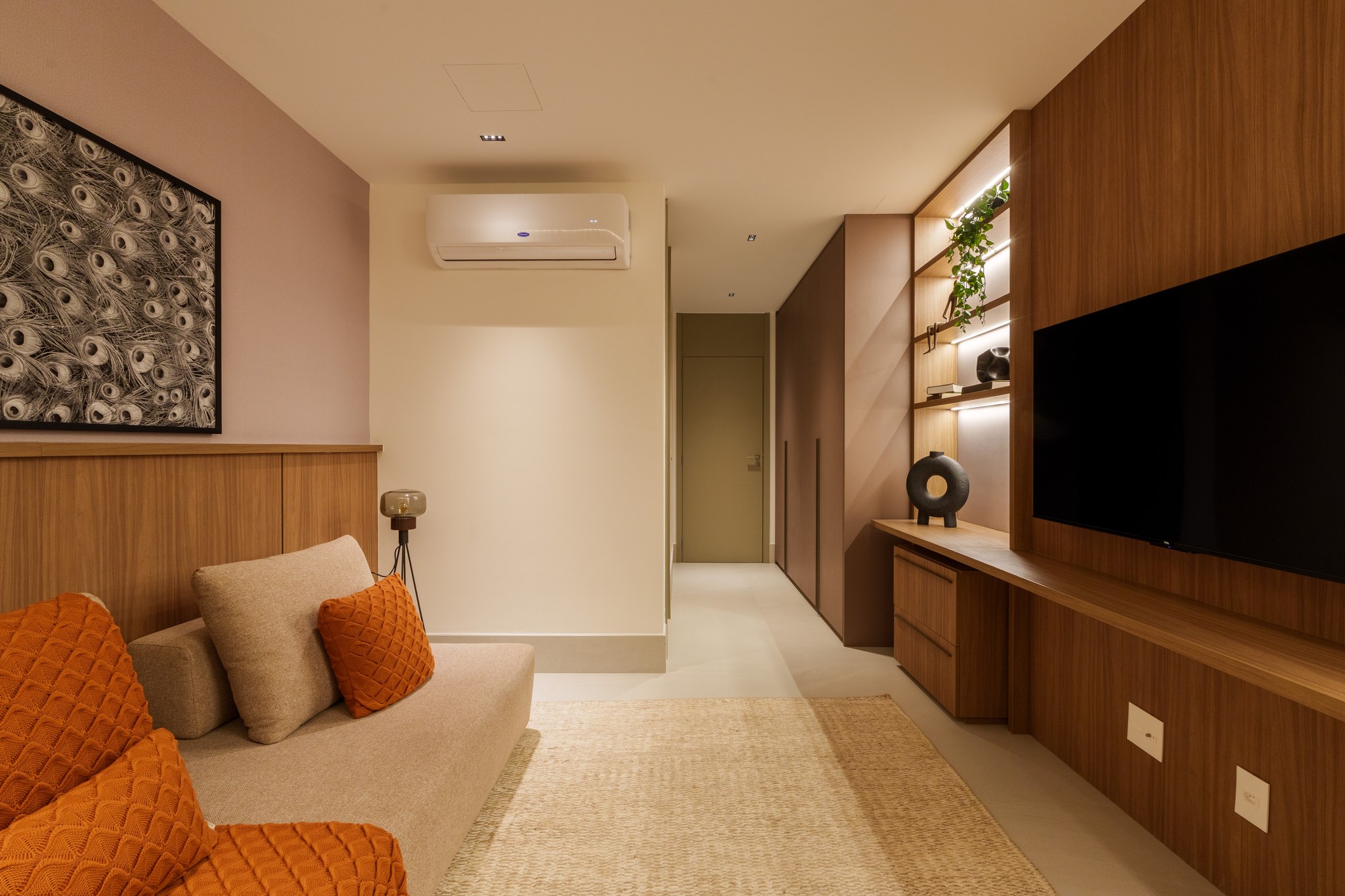 Home theater com sofá bege e poltronas terracota, TV grande na parede em madeira ripada