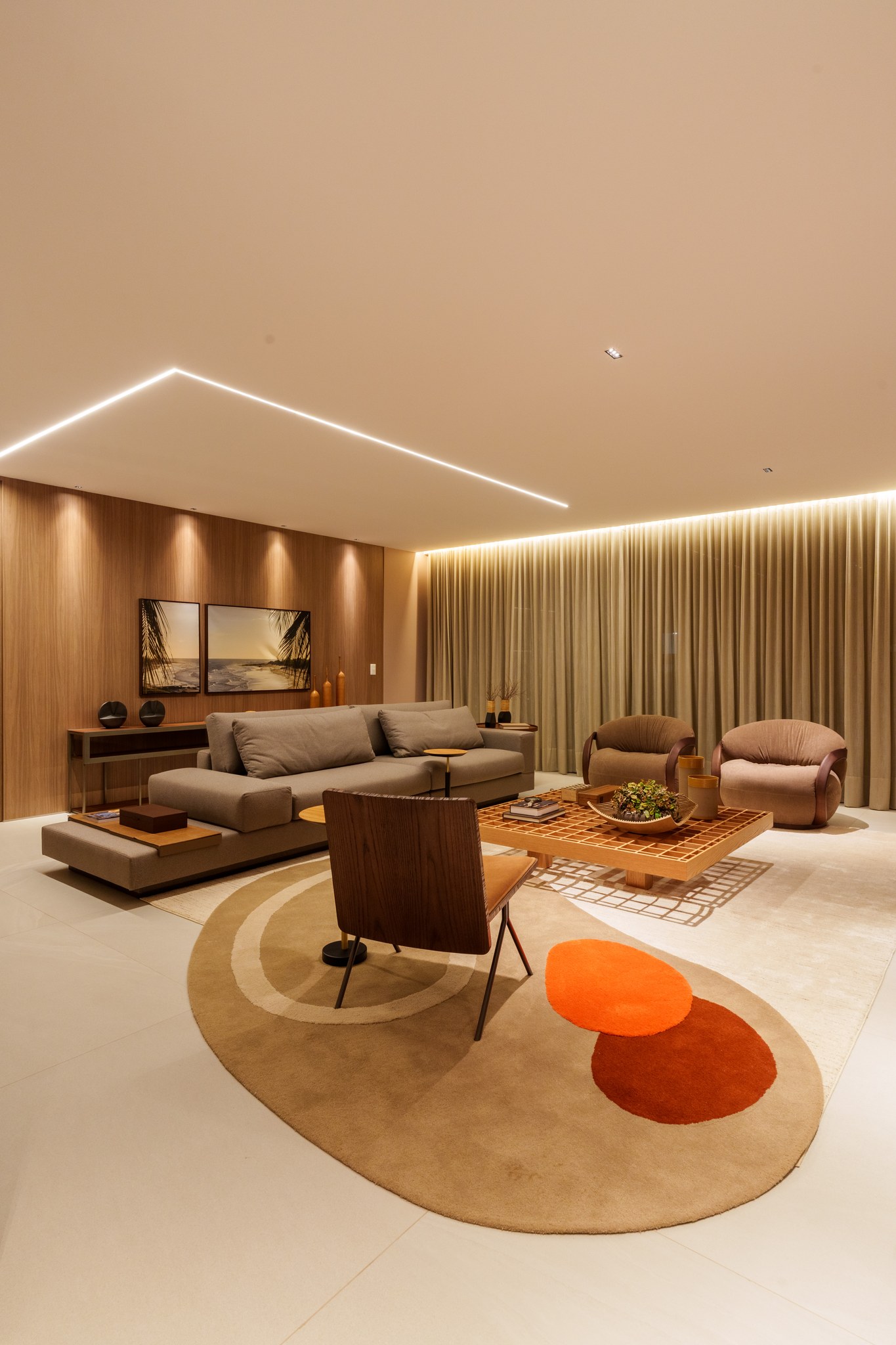 Sala de estar ampla com sofá cinza, poltronas giratórias e tapete orgânico em tons terracota