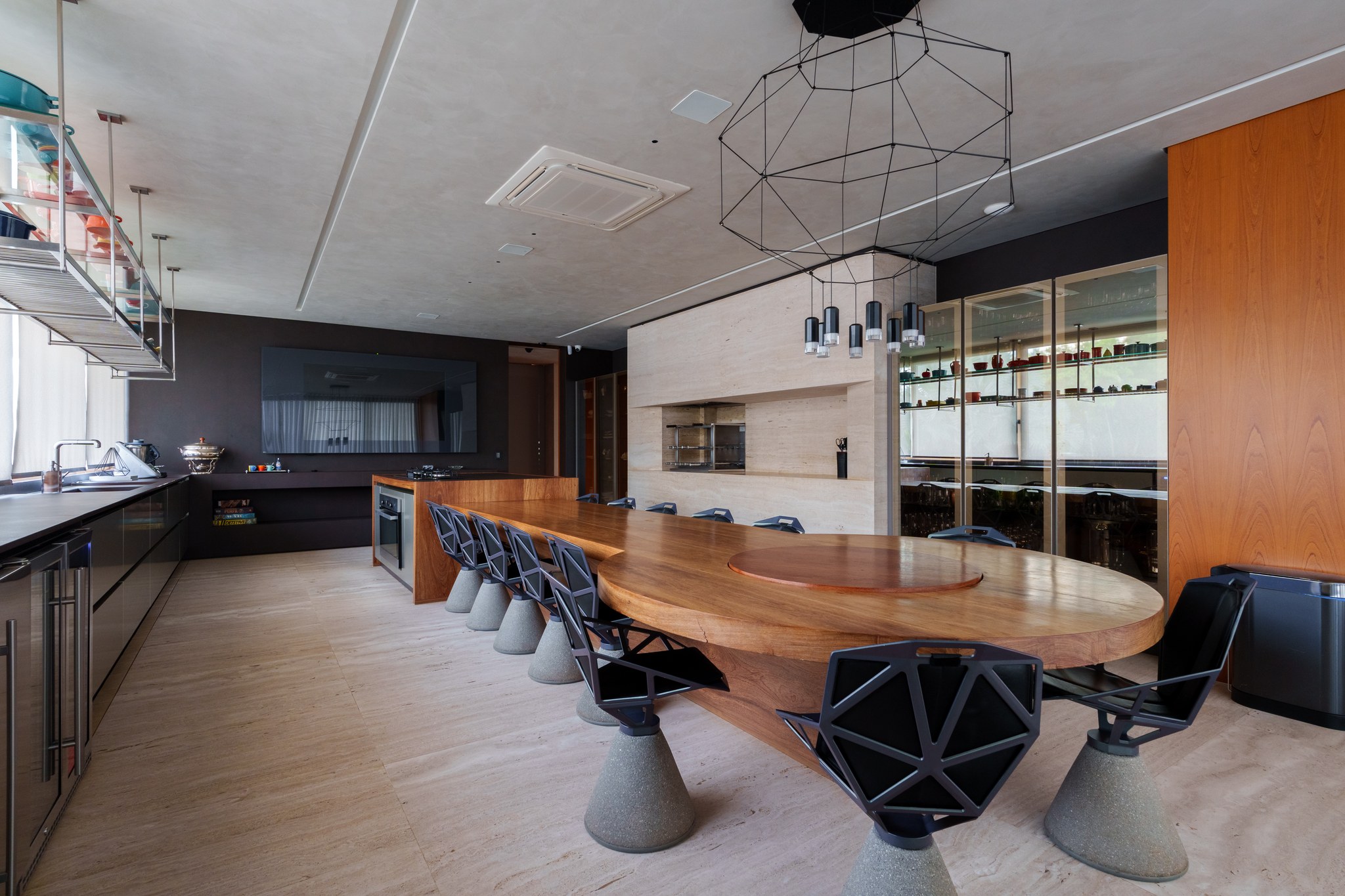 Cozinha gourmet com ilha em madeira, mesa oval para refeições e adega envidraçada