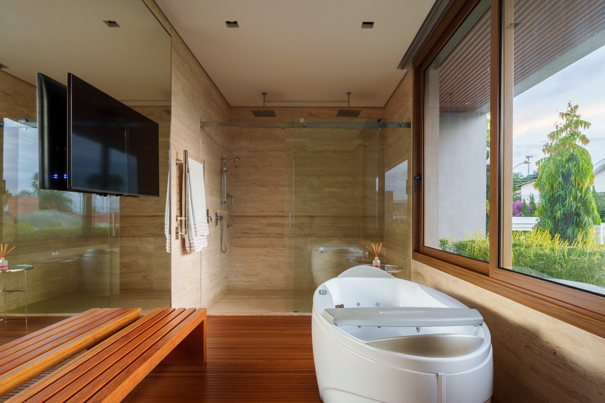 Banheiro com banheira de hidromassagem, box com ducha dupla e vista para o jardim