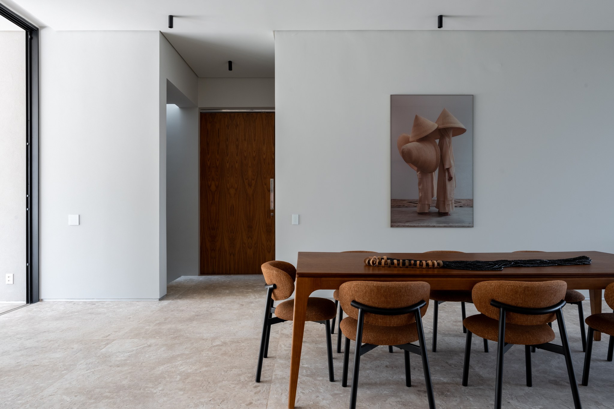 Sala de jantar com retrato contemporâneo, mesa de madeira e cadeiras estofadas em terracota