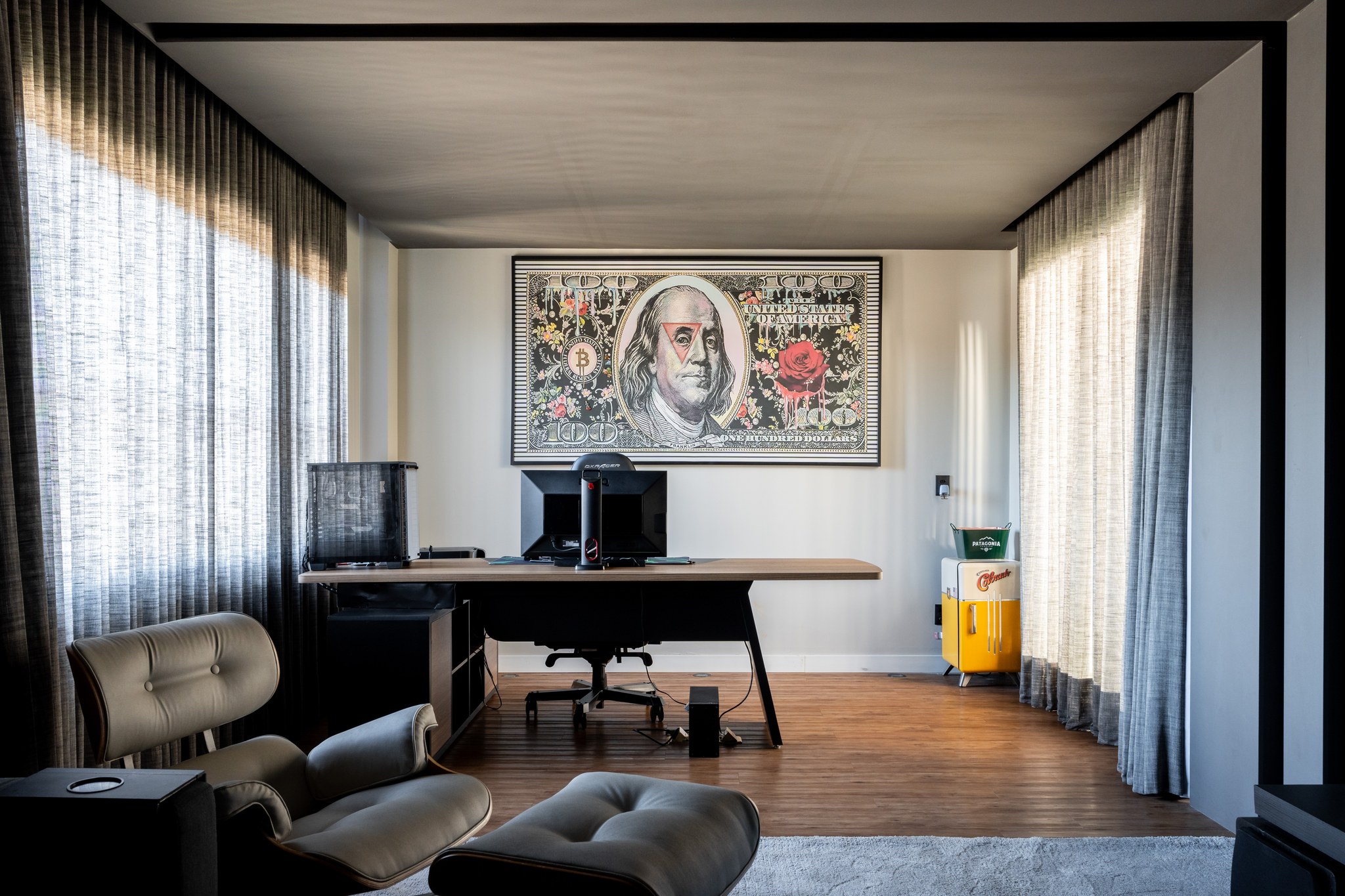Escritório com mesa de trabalho, poltrona Eames e quadro pop art de cédula de cem dólares