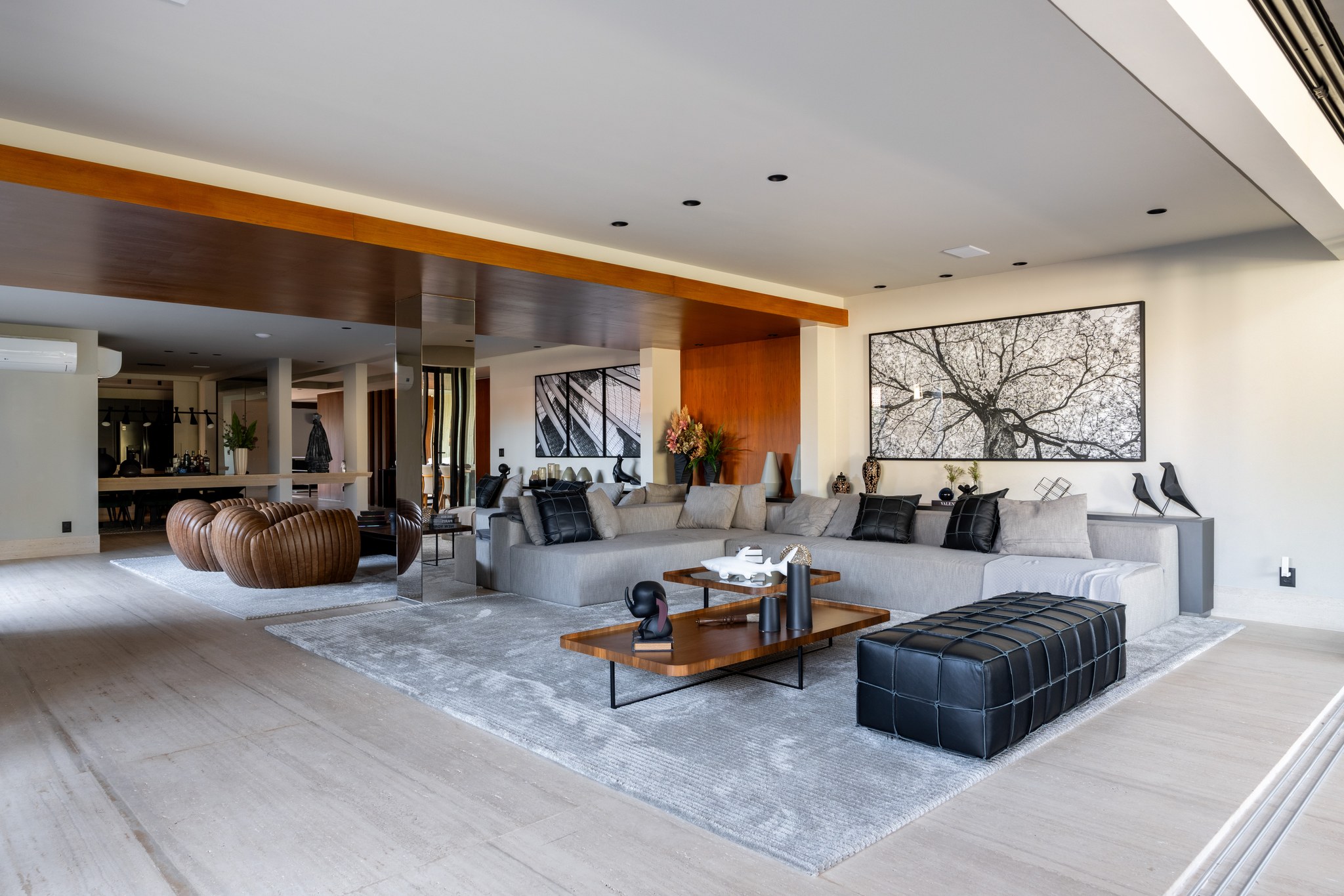 Sala de estar com poltronas de couro caramelo, sofá modular cinza e fotografia de estrutura arquitetônica
