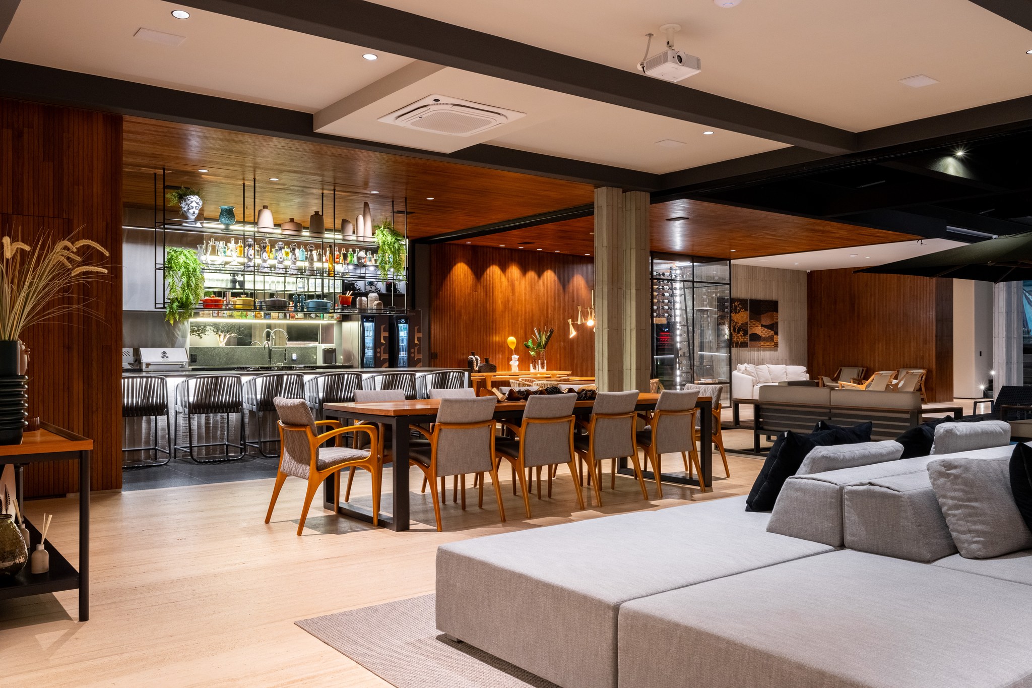Sala de jantar iluminada à noite, com mesa para dez lugares e adega climatizada ao fundo