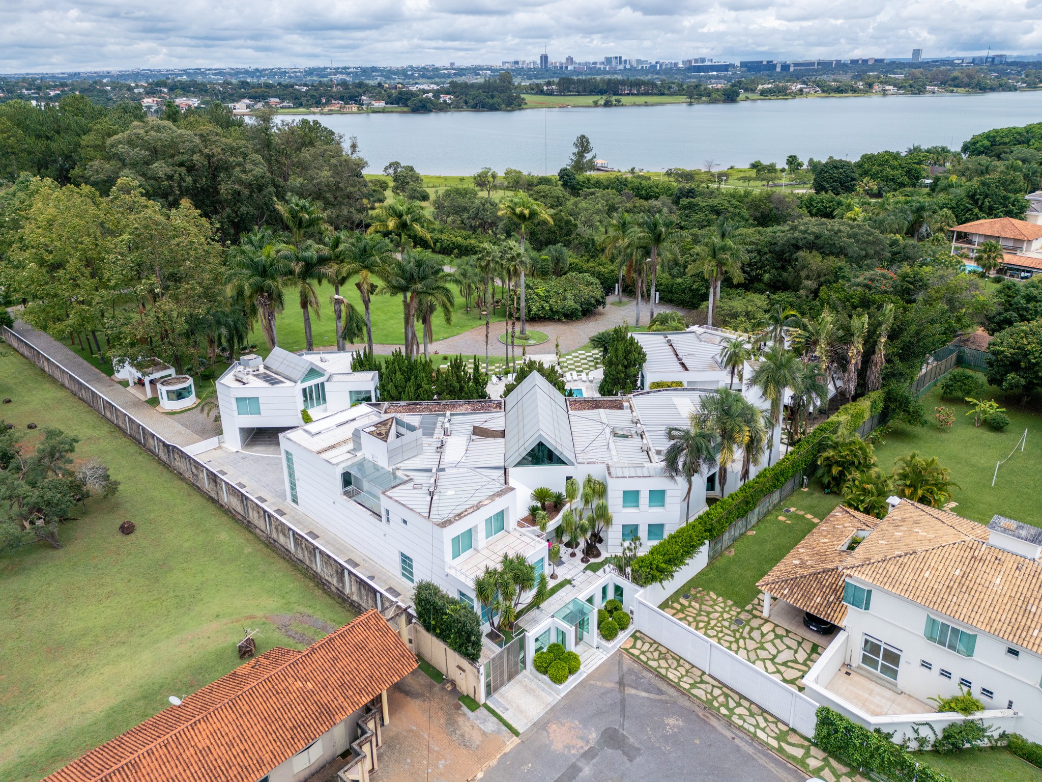 Vista aérea da residência entre lagoa, gramado e vegetação densa do bairro